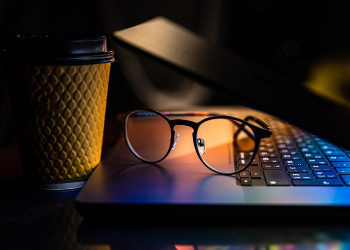 laptop-half-closed-dark-with-colourful-glow-glasses-paper-cup